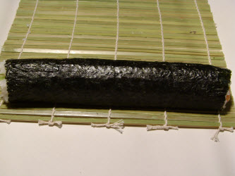 Unroll the sushi mat to show finished chumaki roll