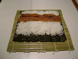 Adding seasoned fried bean curd across rice for futomaki