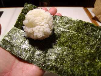 Placing 1/4 cup sushi rice on 4x7 nori sheet for spicy tuna hand roll