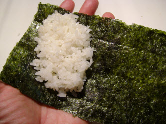 Spreading sushi rice out on nori for hand roll