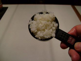 Measuring 1/4 cup of sushi rice for spicy tuna hand roll