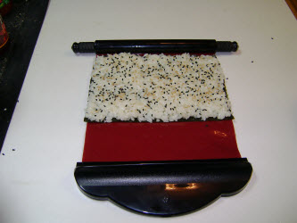 Adding rice to the nori on the sushi magic mat