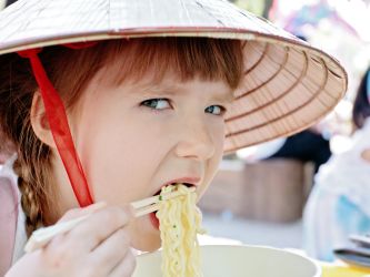 Girl eating noodles with chopsticks