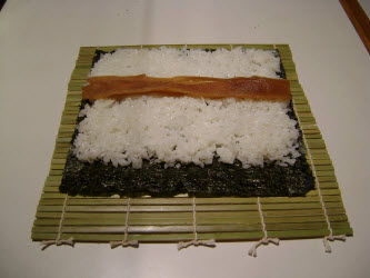 Placing Kanypo seasoned gourd strips across the center of the rice...