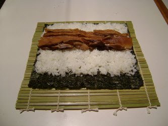 Adding seasoned shitake mushrooms across rice for futomaki