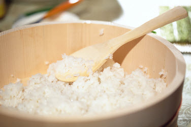 Sushi rice being mixed in a traditional Hangiri (sushi oke)