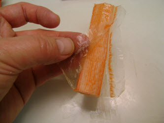 Removing cellophane from crab leg piece