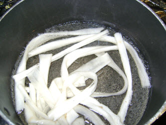 Boiling kampyo gourd strips in water for 10 minutes to soften