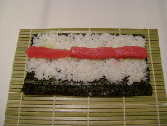 Adding tuna to hosomaki roll