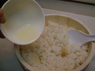 Pour the sushi seasoning all over the hot rice in the hangiri....