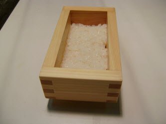 Adding 1/2 cup of rice to oshibako