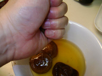 Squeezing excess water out of soaked shitake mushrooms