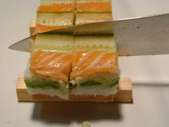 Now, slice across the oshi sushi...you can see I purposely made the cut past the cucumber to make the cut easier and so it will look better