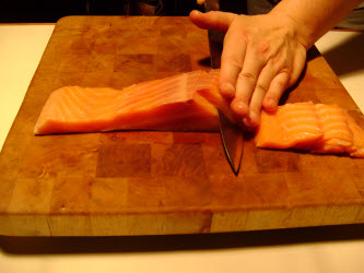 Slicing cold smoked salmon around 3/8 inch thick for maki sushi