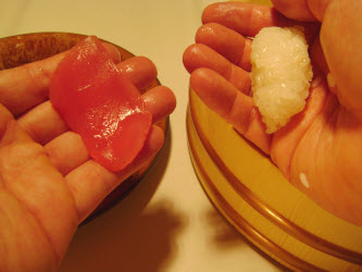 Picking up tuna in left hand and forming an oval with the sushi rice in the right hand