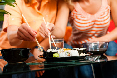 Couple sharing sushi and eating with chopsticks